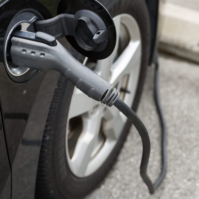 Câble de recharge branché à une voiture électrique sur une borne publique.